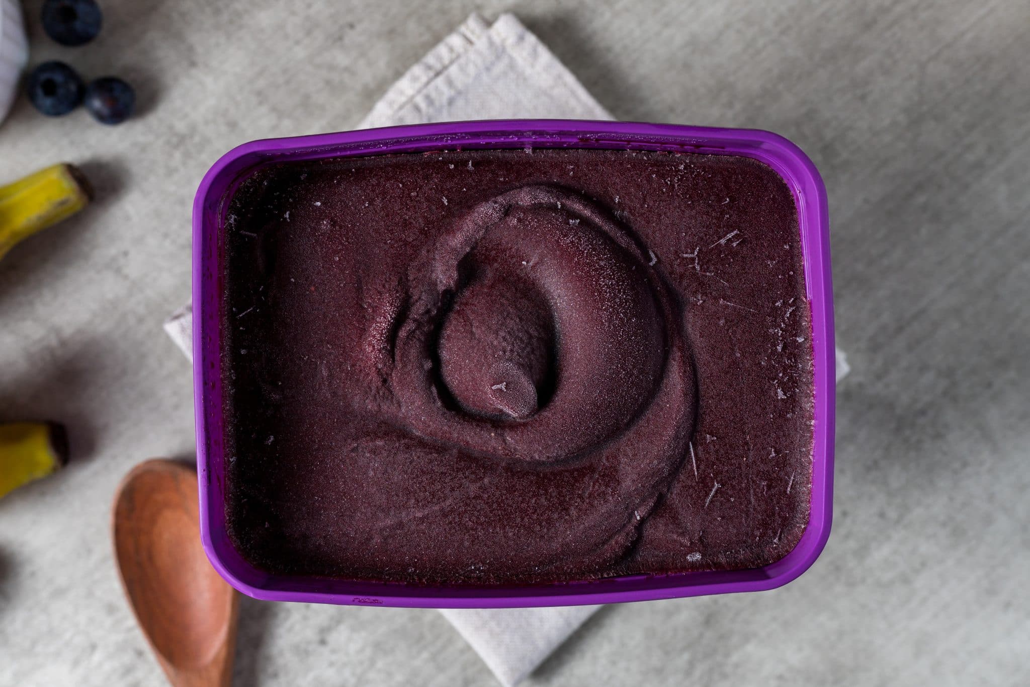 Brazilian frozen açai berry ice cream purple box pot with. with fruits on wooden background. Summer menu top view. close up.