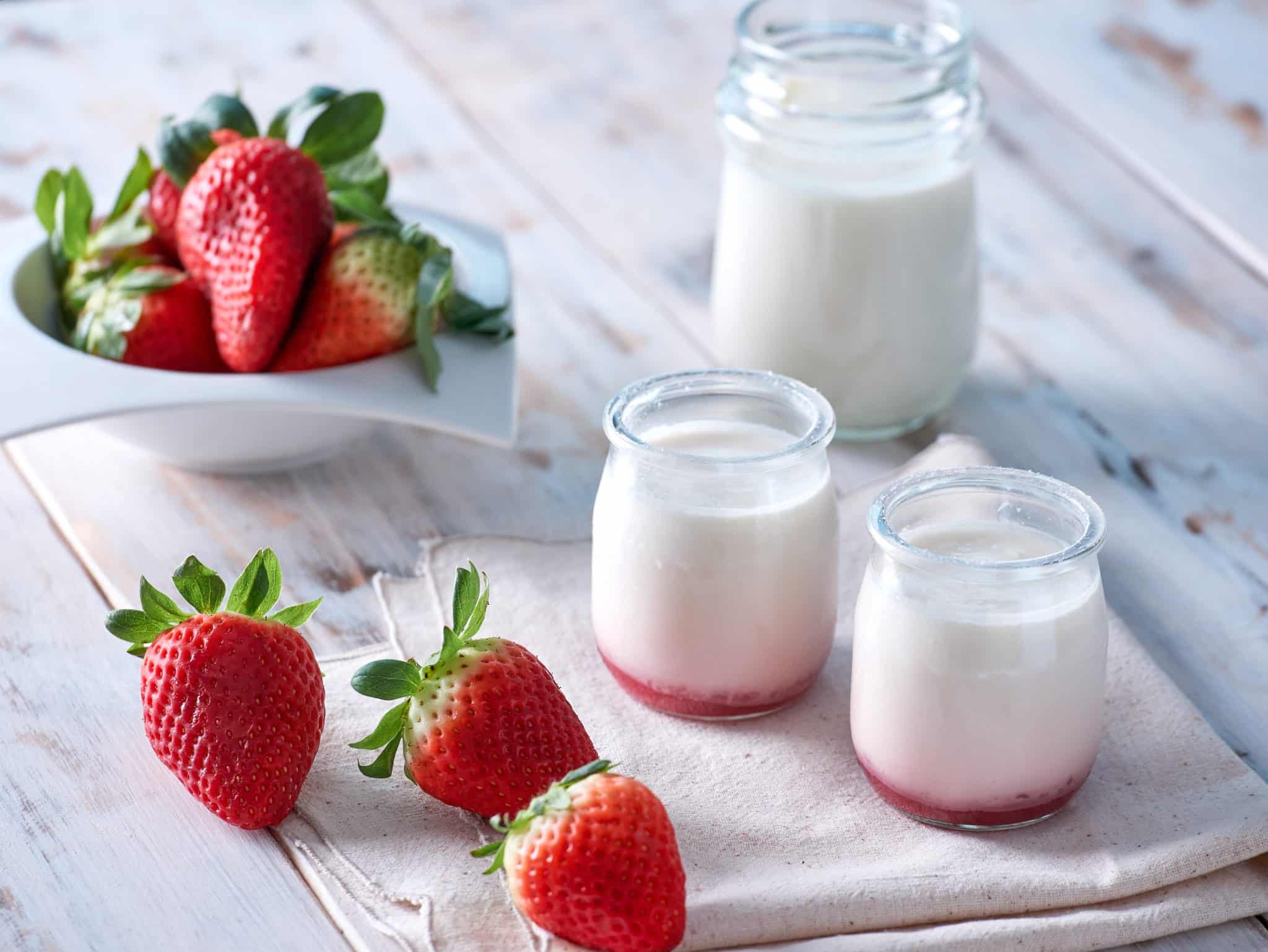 table set with a glass of milk, fresh strawberries and natural yogurt, healthy eating concept