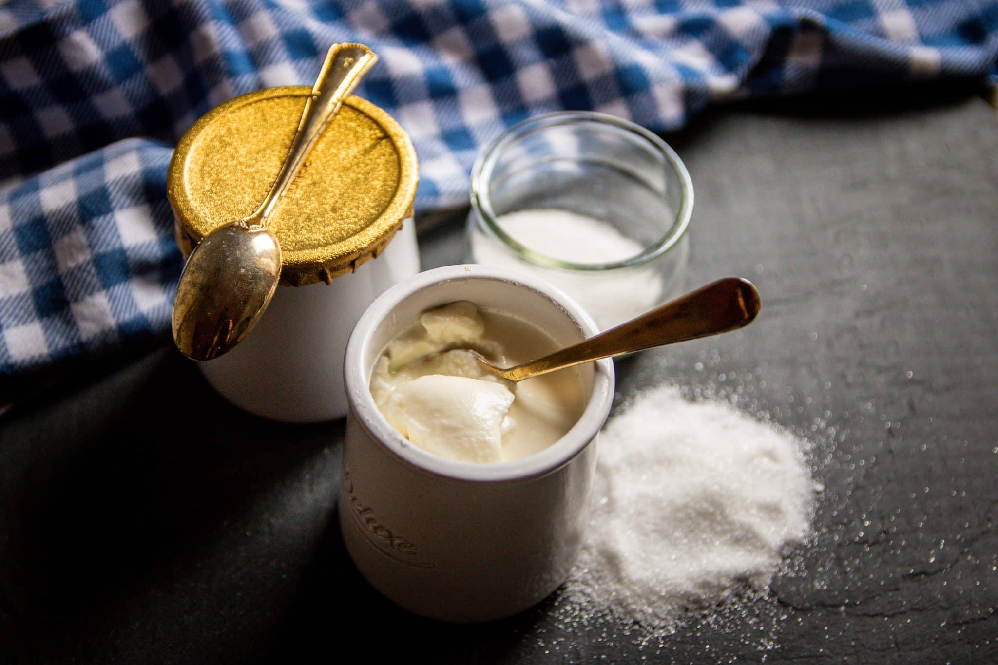 Plain yoghurts in white pots with powdered sugar