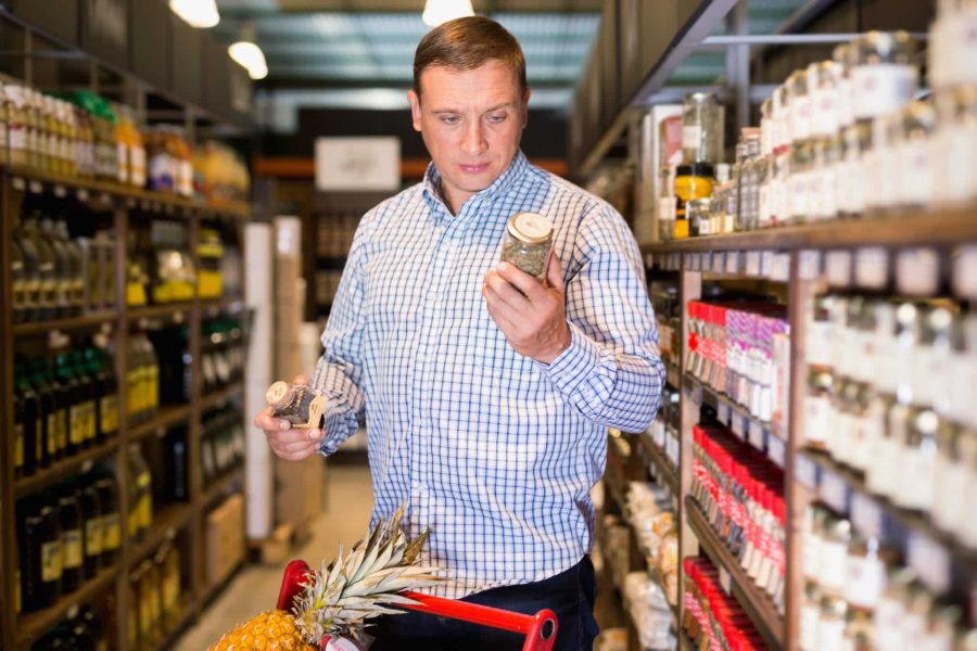 Cheerful glad positive  male customer choosing spices in supermarket